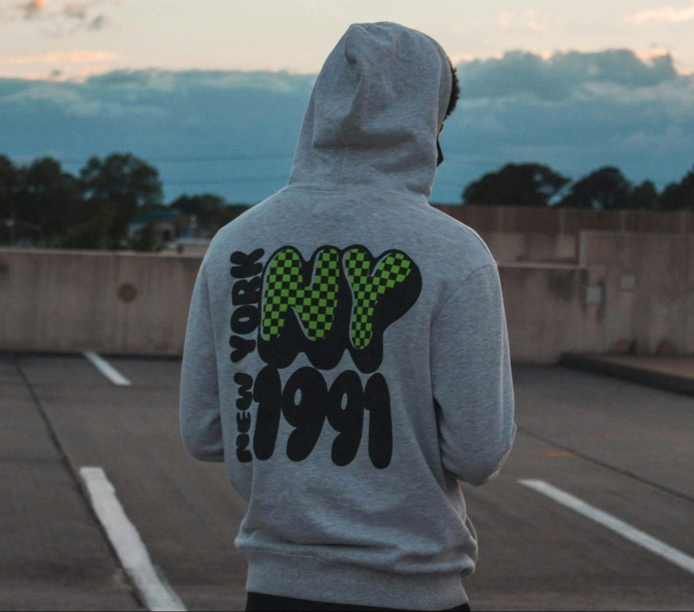 Rear view of Man Wearing Gray Pullover Hoodie and Black Pants at Parking Lot